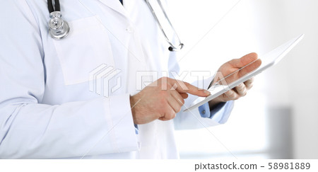 Doctor man using tablet computer for network research or virtual disease treatment, hands close-up 58981889