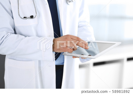 Doctor man using tablet computer for network research or virtual disease treatment, hands close-up Doctor man using tablet computer for network research or virtual disease treatment, hands close-up 58981892