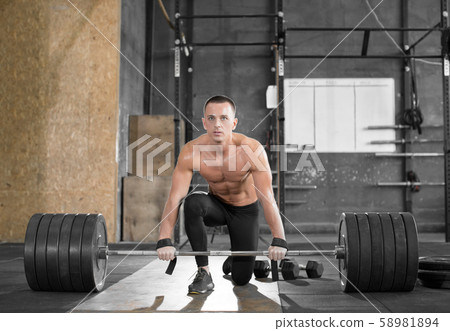 Attractive muscular bodybuilder guy prepare to do exercises with barbell in a gym. Attractive muscular bodybuilder guy prepare to do exercises with barbell in a gym. 58981894
