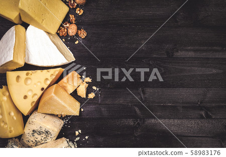 Various types of cheese on black wooden background with copy space 58983176