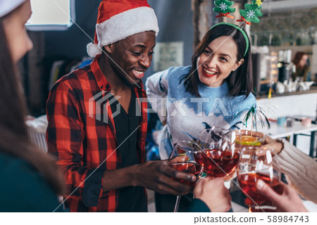 Happy young people with glasses celebrating Christmas or New Year eve. Happy young people with glasses celebrating Christmas or New Year eve. 58984743
