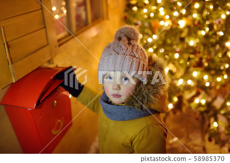 Little boy puts a letter for Santa Claus Little boy puts a letter for Santa Claus 58985370