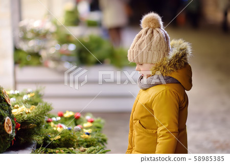 Little boy choosing Christmas wreath Little boy choosing Christmas wreath 58985385