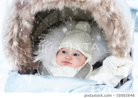 Baby in stroller in winter snow. Kid in pram. Baby in stroller in winter snow. Kid in pram. 58985646