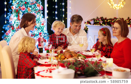 Family with kids having Christmas dinner at tree Family with kids having Christmas dinner at tree 58985759