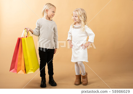 A young girl in a white dress and young boy with shopping bags, happy shopping A young girl in a white dress and young boy with shopping bags, happy shopping 58986029