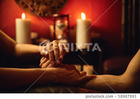 A woman does acupressure fingers for a man. hand massage with intimate lighting. Prelude before 58987891