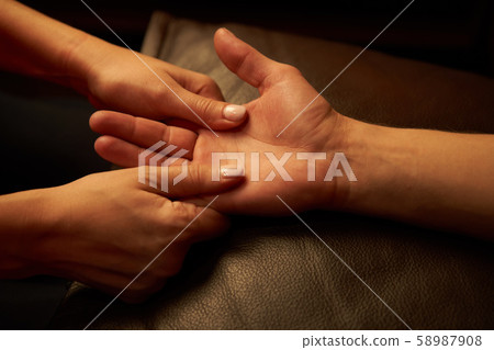A woman does acupressure fingers for a man. hand massage with intimate lighting. Prelude before A woman does acupressure fingers for a man. hand massage with intimate lighting. Prelude before 58987908