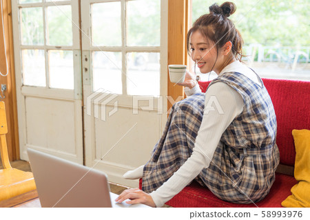 Young woman drinking coffee and looking at computer 58993976