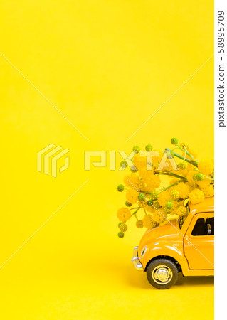 Car toy model delivering bouquet of mimosa flowers Car toy model delivering bouquet of mimosa flowers 58995709