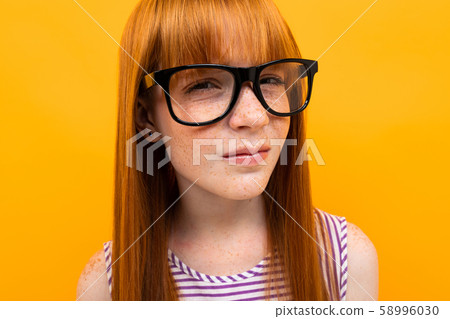 red-haired girl with poor eyesight on a yellow background 58996030