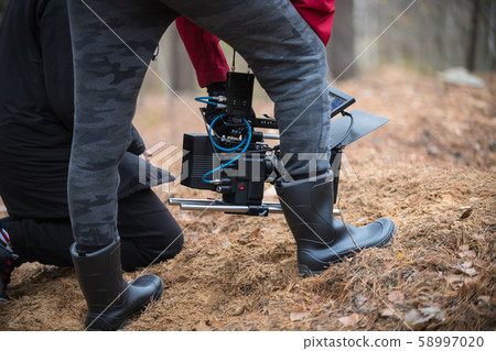 A man with camera in hand is filming in the forest 58997020