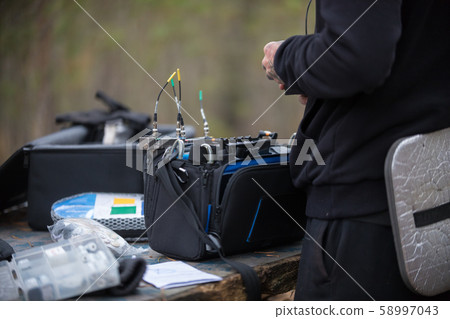 A man is tuning microphone equipment with wires in the forest 58997043