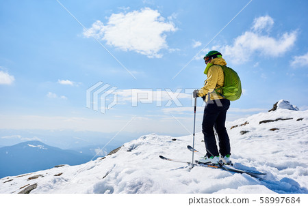 Sportsman skier on skis on background of blue sky and highland landscape. Winter skiing concept. 58997684