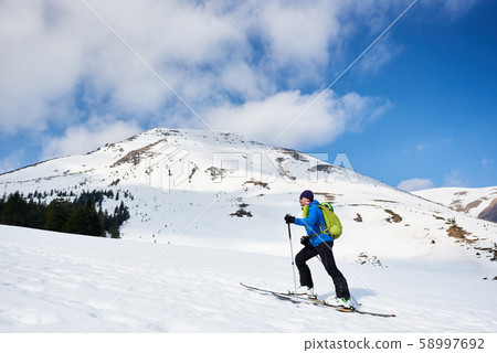Skier tourist with backpack on background of bright blue sky and beautiful mountain panorama. Skier tourist with backpack on background of bright blue sky and beautiful mountain panorama. 58997692
