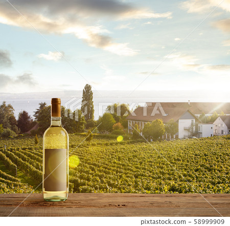 Bottle of wine on wooden rail with country rural scene in background Bottle of wine on wooden rail with country rural scene in background 58999909