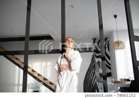 Woman after having bath standing in living room Woman after having bath standing in living room 59001152