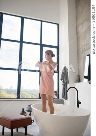 Blonde slim woman covering body in towel after having bath Blonde slim woman covering body in towel after having bath 59001194