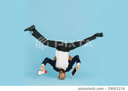 Businessman having fun dancing break dance on blue background at work Businessman having fun dancing break dance on blue background at work 59001216