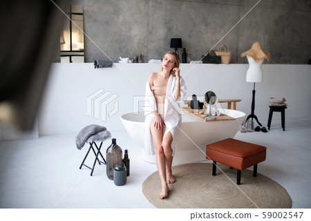 Slim woman wearing underwear doing makeup in the bathroom Slim woman wearing underwear doing makeup in the bathroom 59002547