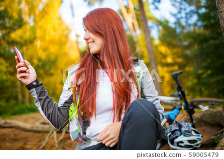 Photo of happy woman with cell phone in autumn forest 59005479