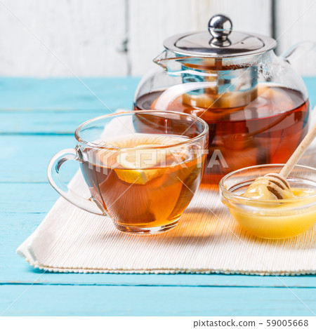 Glass cup of tea with lemon, glass teapot and honey. Glass cup of tea with lemon, glass teapot and honey. 59005668