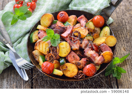 Fried unpeeled baby potatoes with cured pork neck and vegetables, served in an iron frying pan Fried unpeeled baby potatoes with cured pork neck and vegetables, served in an iron frying pan 59006148