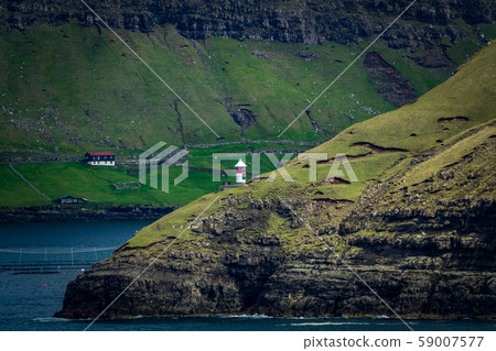 Isolated autonomous small lighthouse in Faroe Islands coast 59007577