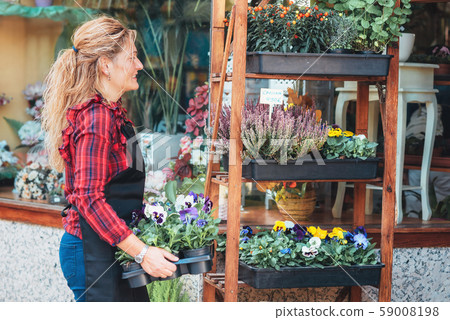 Young beautiful florist posing, smiling among plants.  59008198