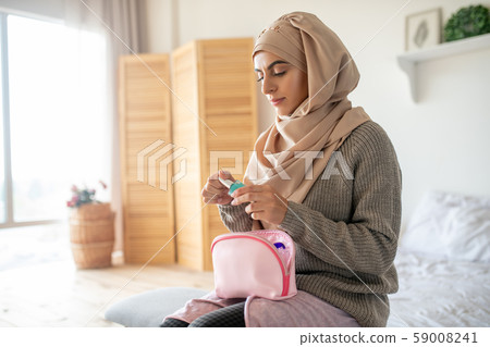 Young girl wearing hijab using her new nail polish 59008241