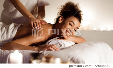 Excited black woman receiving back massage in spa Excited black woman receiving back massage in spa 59008859