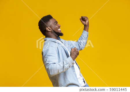Portrait of excited african guy celebrating success with clenched fists Portrait of excited african guy celebrating success with clenched fists 59011445