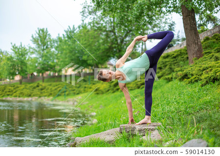 A young sports girl practices yoga on a green lawn A young sports girl practices yoga on a green lawn 59014130