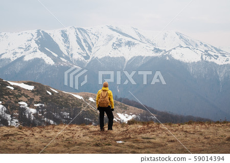 Man with backpack in spring snowy mountains 59014394