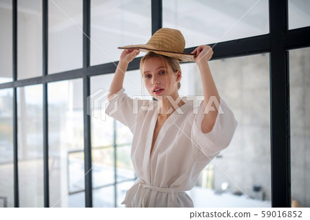 Blonde woman holding straw hat while choosing straw hat Blonde woman holding straw hat while choosing straw hat 59016852