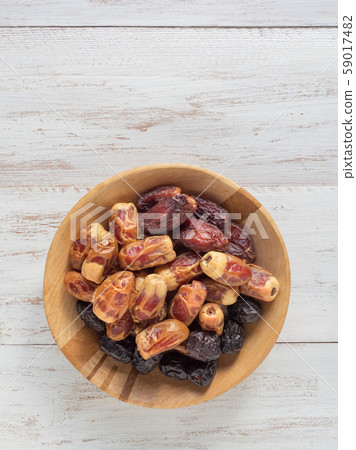 Dates in wooden bowl on white rustic background. Dates in wooden bowl on white rustic background. 59017482