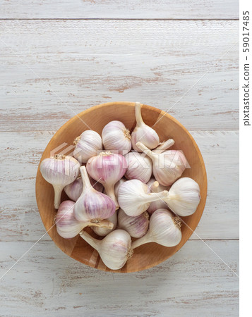 Garlic in a wooden bowl on a white wooden table. Garlic in a wooden bowl on a white wooden table. 59017485