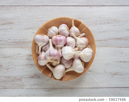 Garlic in a wooden bowl on a white wooden table. Garlic in a wooden bowl on a white wooden table. 59017486