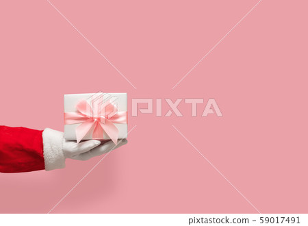 Santa Claus hand holding gift box on pink isolated Santa Claus hand holding gift box on pink isolated 59017491