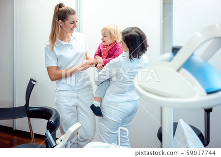 Dentist and her assistant with child in the office 59017744