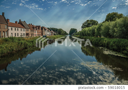 Houses and grove along canal with sky reflected on water Houses and grove along canal with sky reflected on water 59018015
