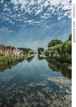 Houses and grove along canal with sky reflected on water Houses and grove along canal with sky reflected on water 59018017