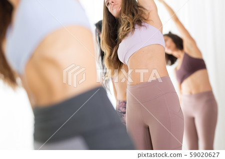 Group of young sporty attractive women in yoga studio, practicing yoga lesson with instructor 59020627