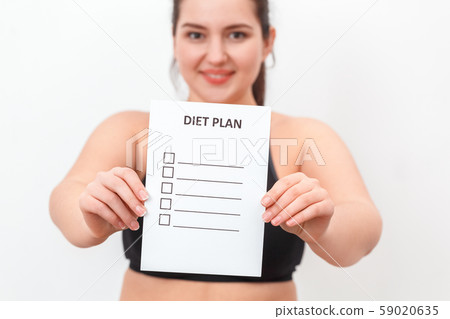 Body Care. Chubby girl standing isolated on white showing diet plan to camera close-up smiling happy Body Care. Chubby girl standing isolated on white showing diet plan to camera close-up smiling happy 59020635