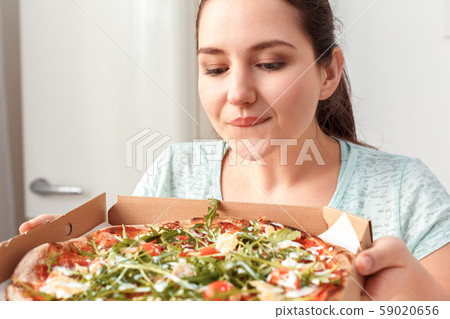 Fastfood. Chubby girl sitting at kitchen table anticipating the taste of pizza excited close-up 59020656