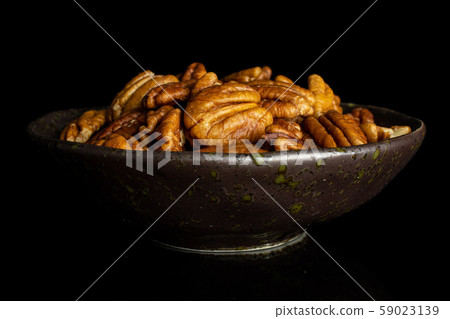 Dry brown pecan nut isolated on black glass Dry brown pecan nut isolated on black glass 59023139