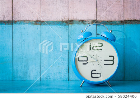 Blue vintage alarm clocks on blue wooden table and light blue and pink background wall 59024406