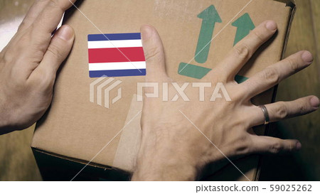 Warehouse worker places sticker with flag of Costa Rica on the box. Costa Rican import or export 59025262