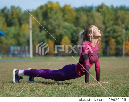 Woman doing yoga exercises and stretching on the grass outdoor in a park. 59026456