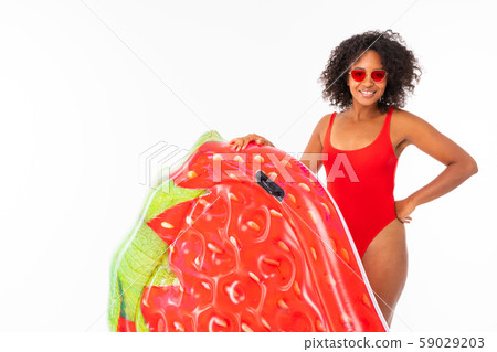 African American in a red bathing suit on a white background with a mattress for the pool in her African American in a red bathing suit on a white background with a mattress for the pool in her 59029203